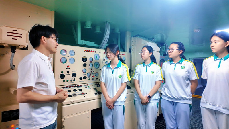 在航母舱室中，学生们聆听讲解，了解航母构造。艾弗森贝博ballbet官网供图